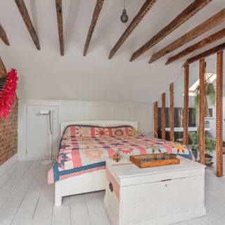 A brick-walled master bedroom with wooden beams exposed
