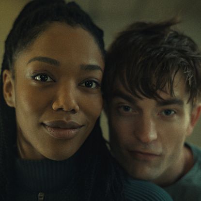 robert pattinson leaning his head on naomi ackie's shoulder as mickey and nasha in mickey 17