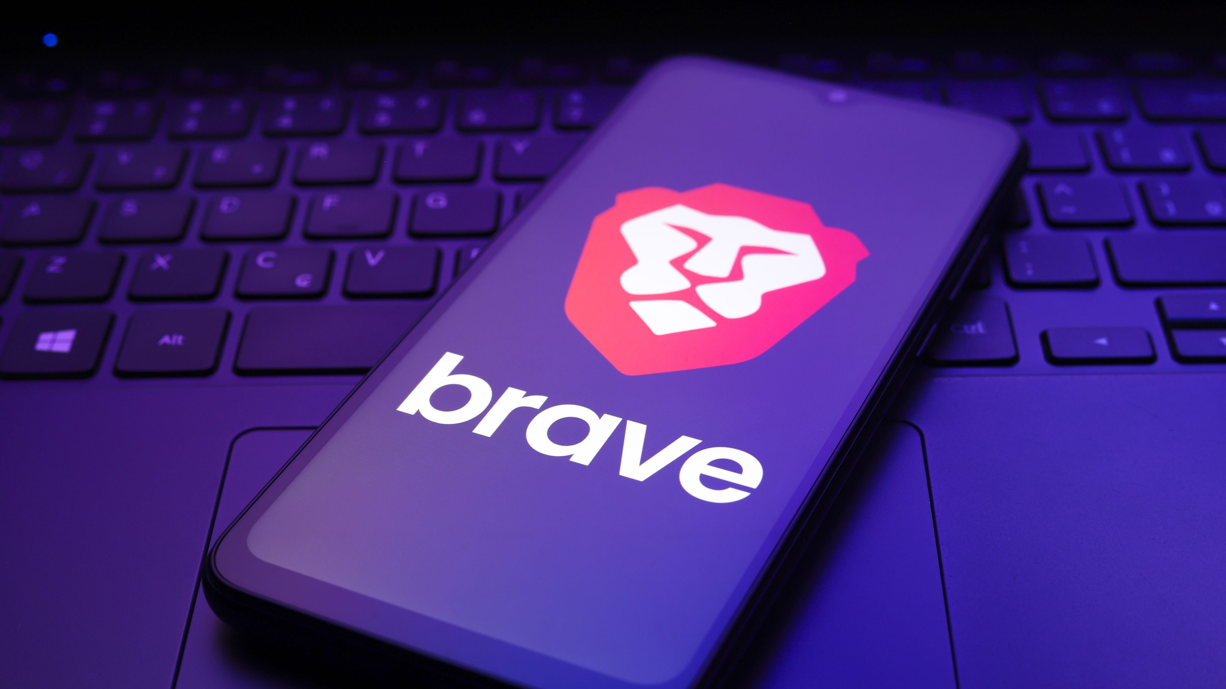 The Brave browser logo appears on the screen of a smartphone.