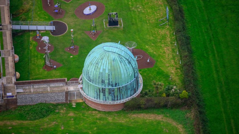 a round, domed building stained green with patina is surrounded by lush green pastures