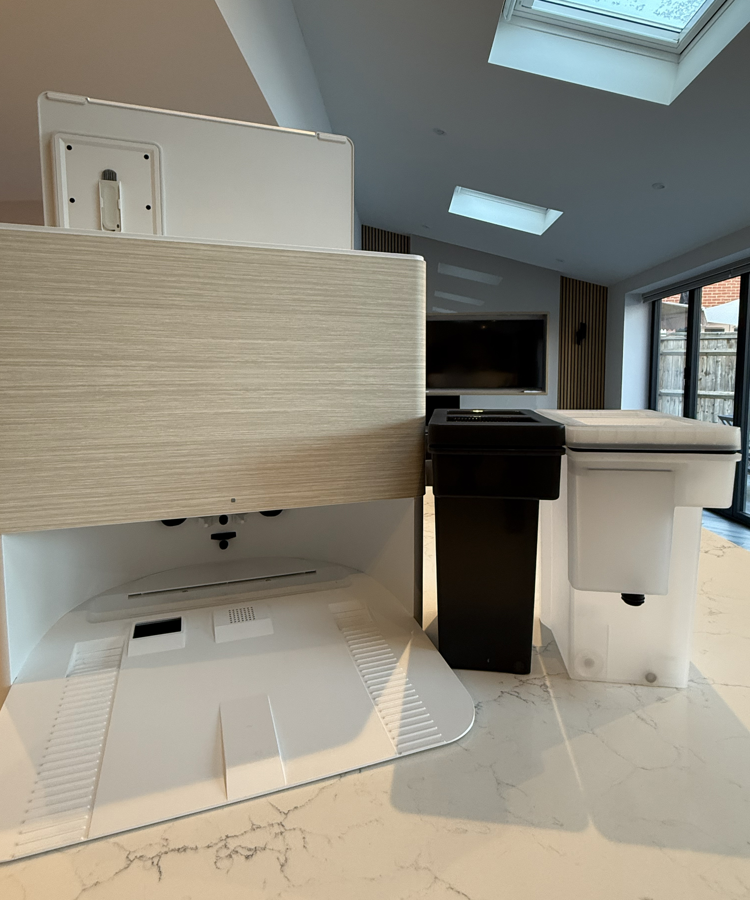The Roomba Max 705 Dock is pictured next to the black dirty water tank, and the white clean water tank