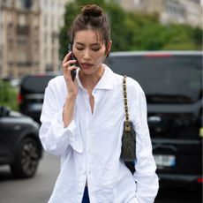 Liu Wen wears a white shirt, blue pants and olive green Chanel bag
