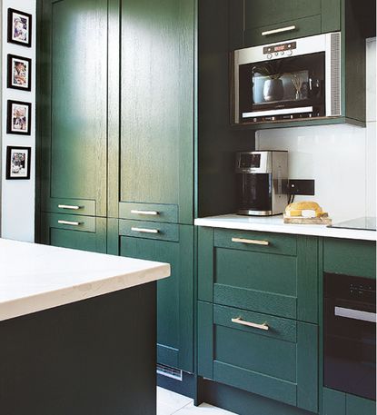 Green kitchen cabinets with white worktops