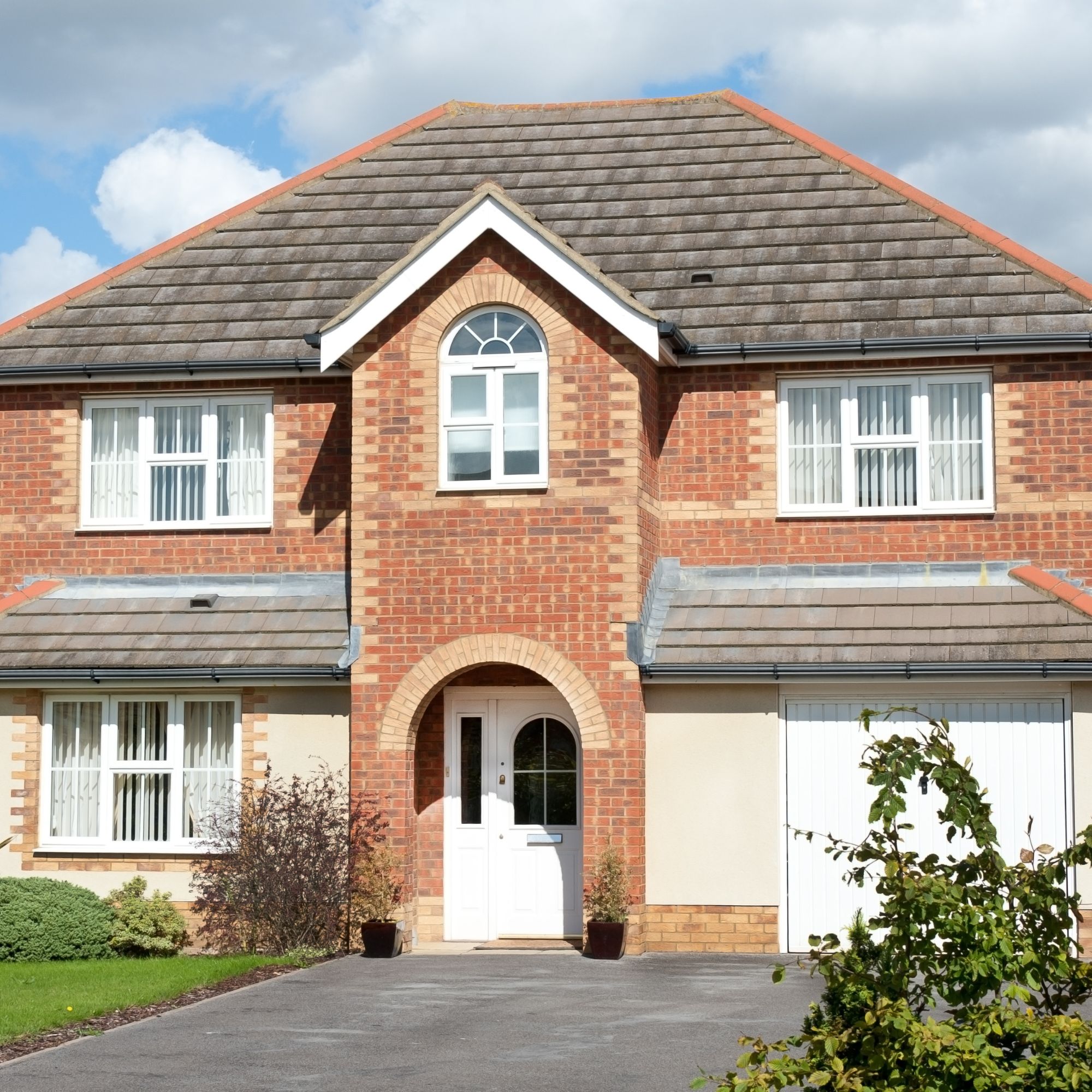 Large brick house with tarmac driveway and plants