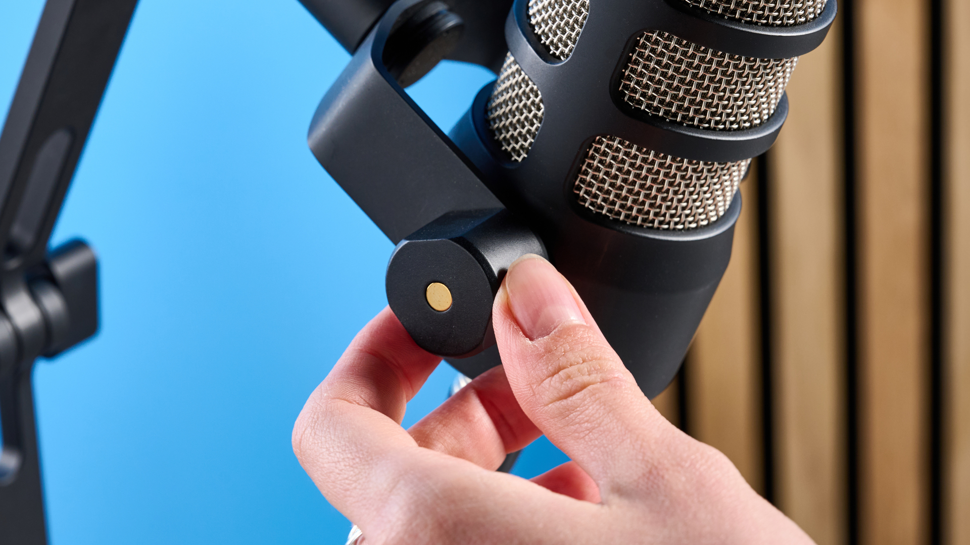 the rode podmic podcast and broadcast microphone photographed with a blue background, shown with the rode ds2 desk stand