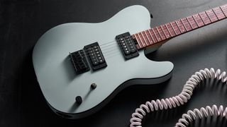 A Charvel Standard Series San Dimas Style 2 SD2 HH HT electric guitar lying on a dark floor with a coiled guitar cable next to it
