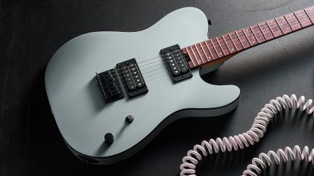 A Charvel Standard Series San Dimas Style 2 SD2 HH HT electric guitar lying on a dark floor with a coiled guitar cable next to it