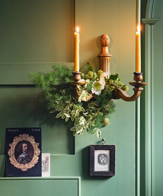 Christmas wall decor ideas with sage green walls and foliage wrapped aroound a candle wall sconce