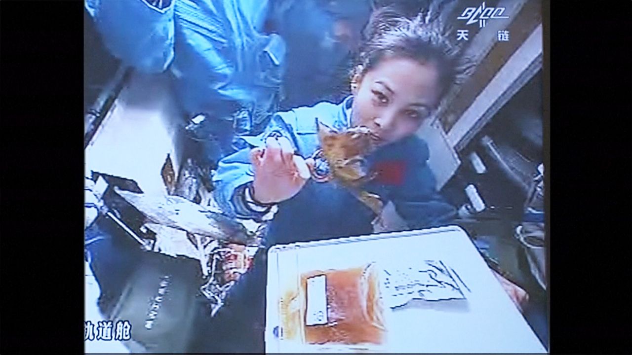 A still image of a Chinese astronaut eating in space.