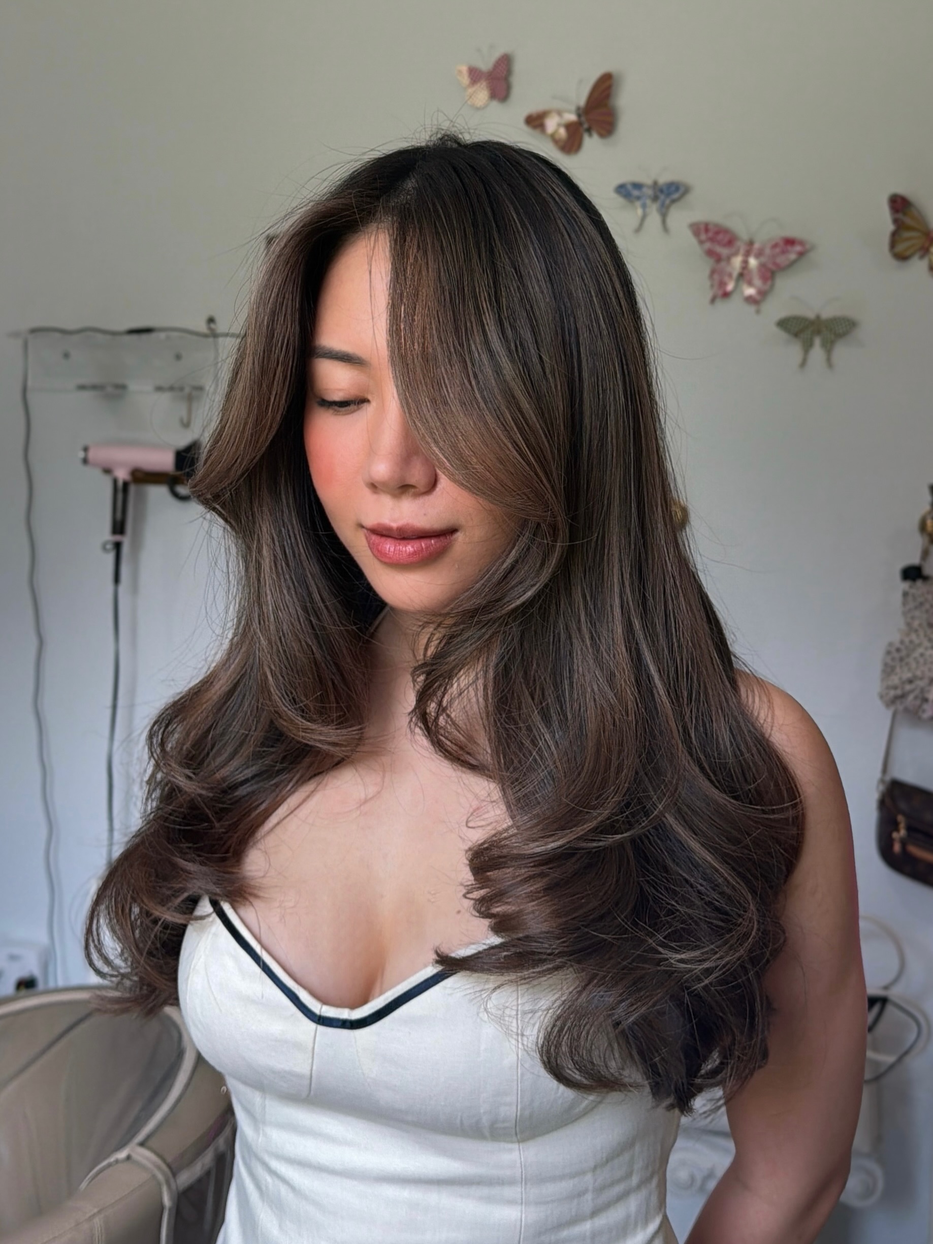 woman with brunette hair thats curled and a white and black tank top