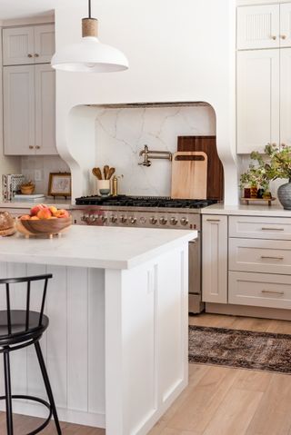 A white, cozy kitchen with a plaster kitchen hood