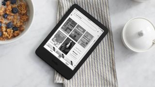 The 2022 Amazon Kindle ereader lying on a tea towel beside a bowl of cereal