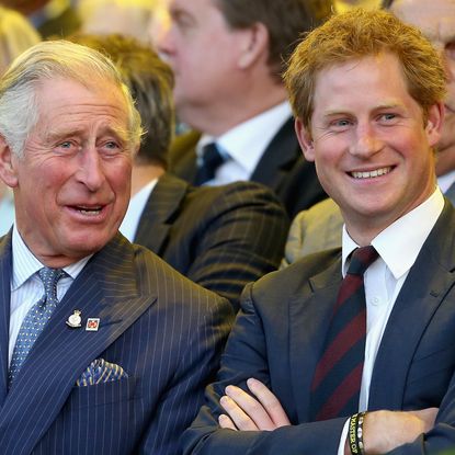 King Charles and Prince Harry laugh while wearing suits at the Invictus Games in 2014