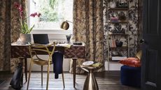 Maximalist home office by John Lewis and Partners, with patterned wallpaper, patterned curtains, and patterned blinds, a desk with a geometric chair, and a bronze side table
