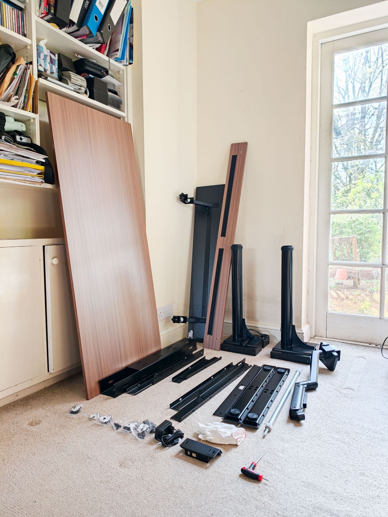 All of the pieces for the build of the Arozzi Arena Nordico Electric Standing Desk laid out in office room