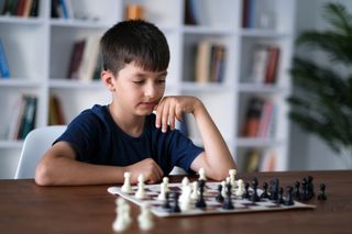 Young boy thinking about his next move when playing chess