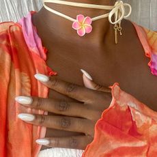 A woman with milky nails and a floral necklace
