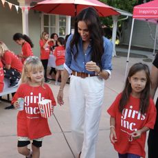 meghan markle walks with two girls wearing a blue j crew shirt and white pants