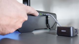 A hand pressing the button on the side of the Razer Monitor Stand Chroma