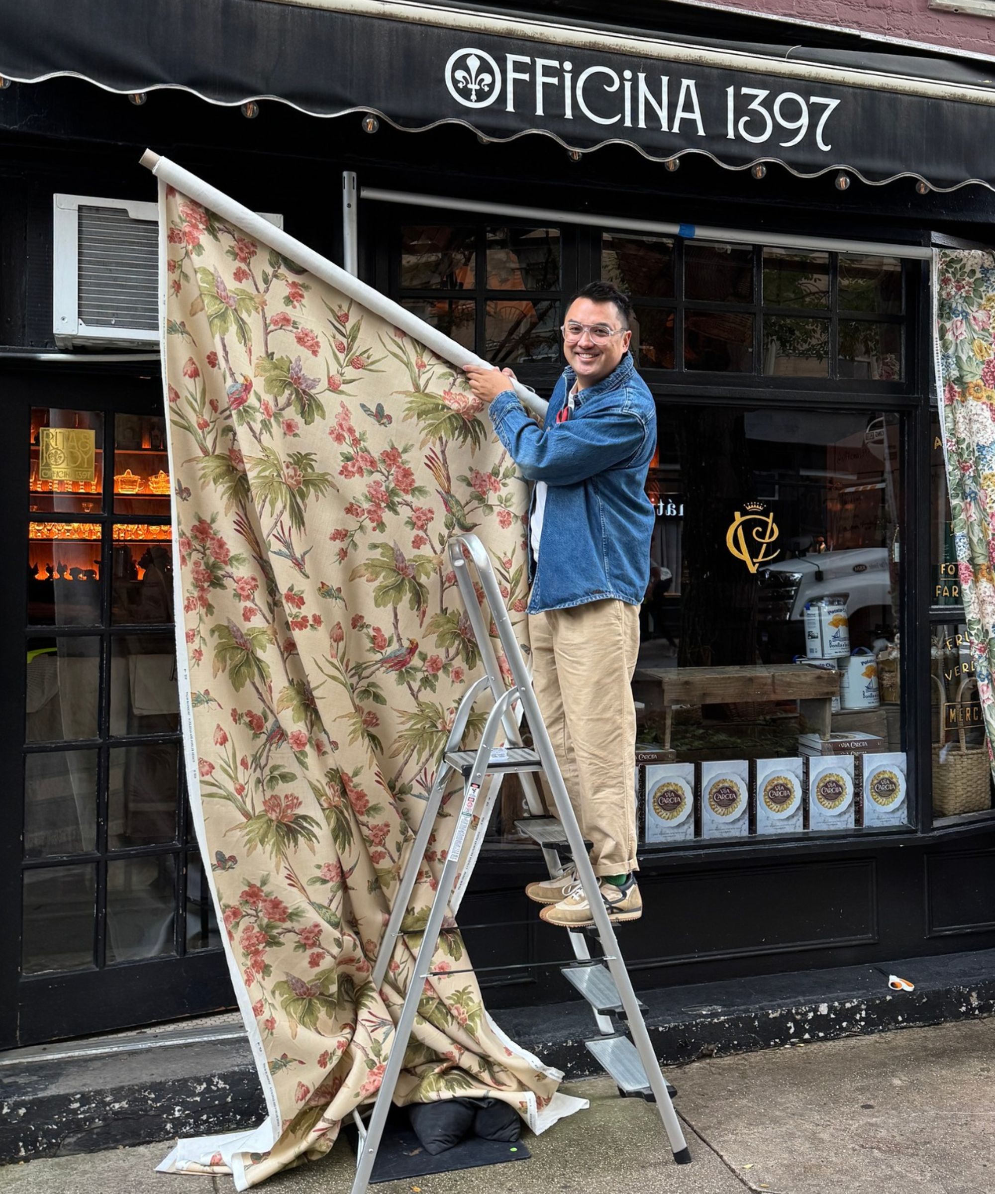 Ben Reynaert on a step ladder dressing Officina 1397 with fabrics for a pop up