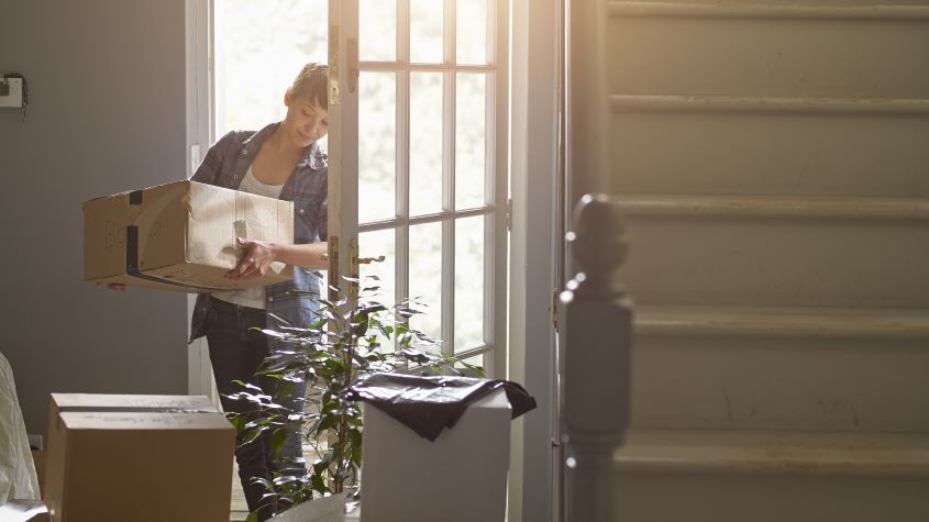 Woman carrying boxes into a house