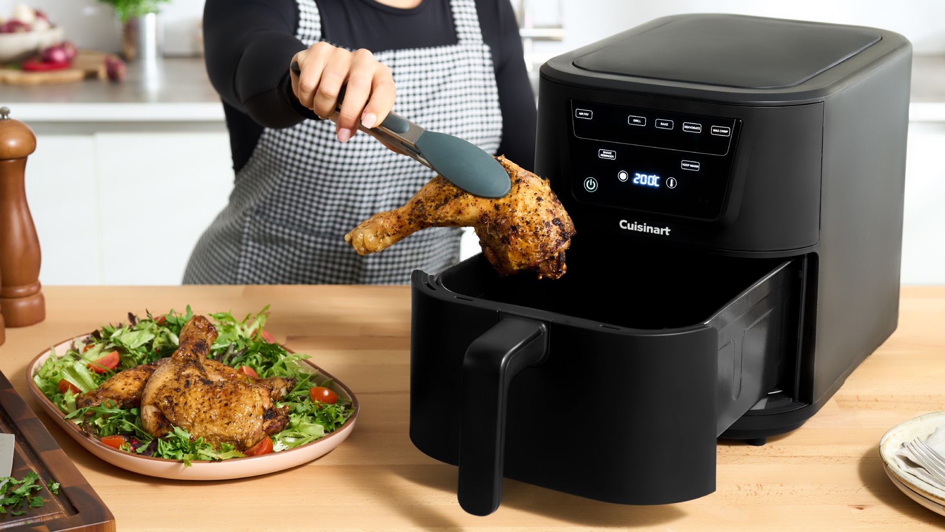 Person with tongs removing chicken leg from air Cuisinart fryer