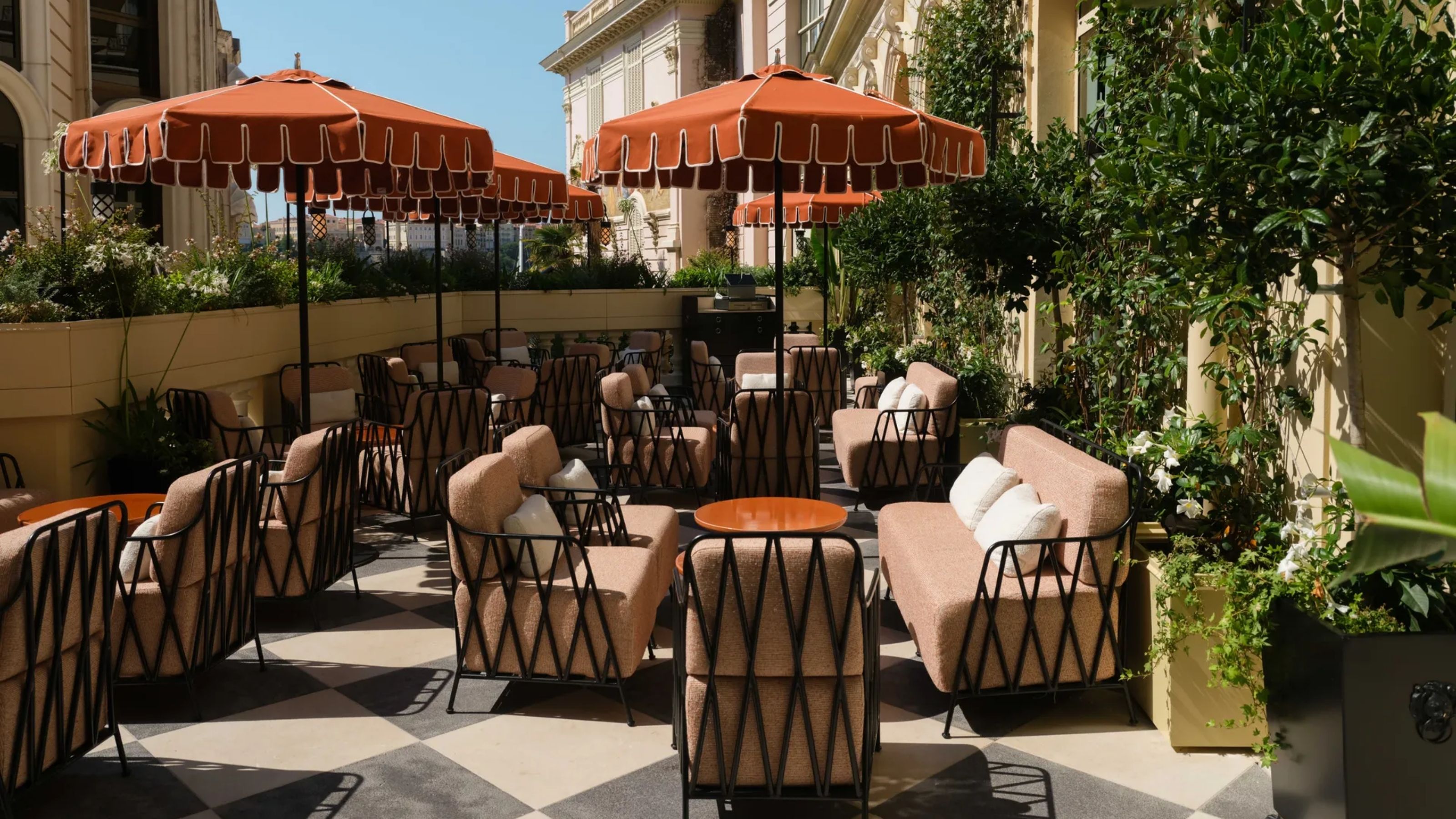  A terrace at a hotel in Monaco with checkered floors and burnt-orange parasols.