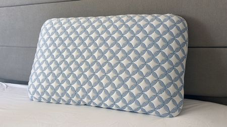 The Helix Cooling Memory Foam Pillow resting against the bed frame in our reviewer's bedroom