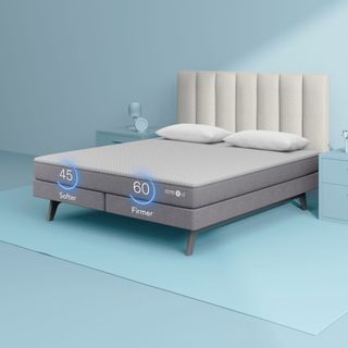 Sleep Number c2 Smart Bed on a gray bed frame on a blue carpet against a blue wall.