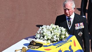 WINDSOR, UNITED KINGDOM - APRIL 17: (EMBARGOED FOR PUBLICATION IN UK NEWSPAPERS UNTIL 24 HOURS AFTER CREATE DATE AND TIME) Prince Charles, Prince of Wales follows Prince Philip, Duke of Edinburgh's coffin (draped in his Royal Standard Flag and bearing his Royal Navy cap, sword and a bouquet of lilies, white roses, freesia and sweet peas) as it is carried on a specially designed Land Rover Defender hearse during his funeral procession to St. George's Chapel, Windsor Castle on April 17, 2021 in Windsor, England. Prince Philip of Greece and Denmark was born 10 June 1921, in Greece. He served in the British Royal Navy and fought in WWII. He married the then Princess Elizabeth on 20 November 1947 and was created Duke of Edinburgh, Earl of Merioneth, and Baron Greenwich by King VI. He served as Prince Consort to Queen Elizabeth II until his death on April 9 2021, months short of his 100th birthday. His funeral takes place today at Windsor Castle with only 30 guests invited due to Coronavirus pandemic restrictions.
