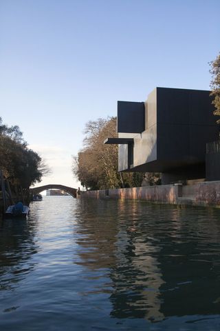 The granite-clad volume includes a dramatic cantilever over the canal