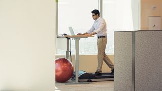 man using an under desk treadmill as he works