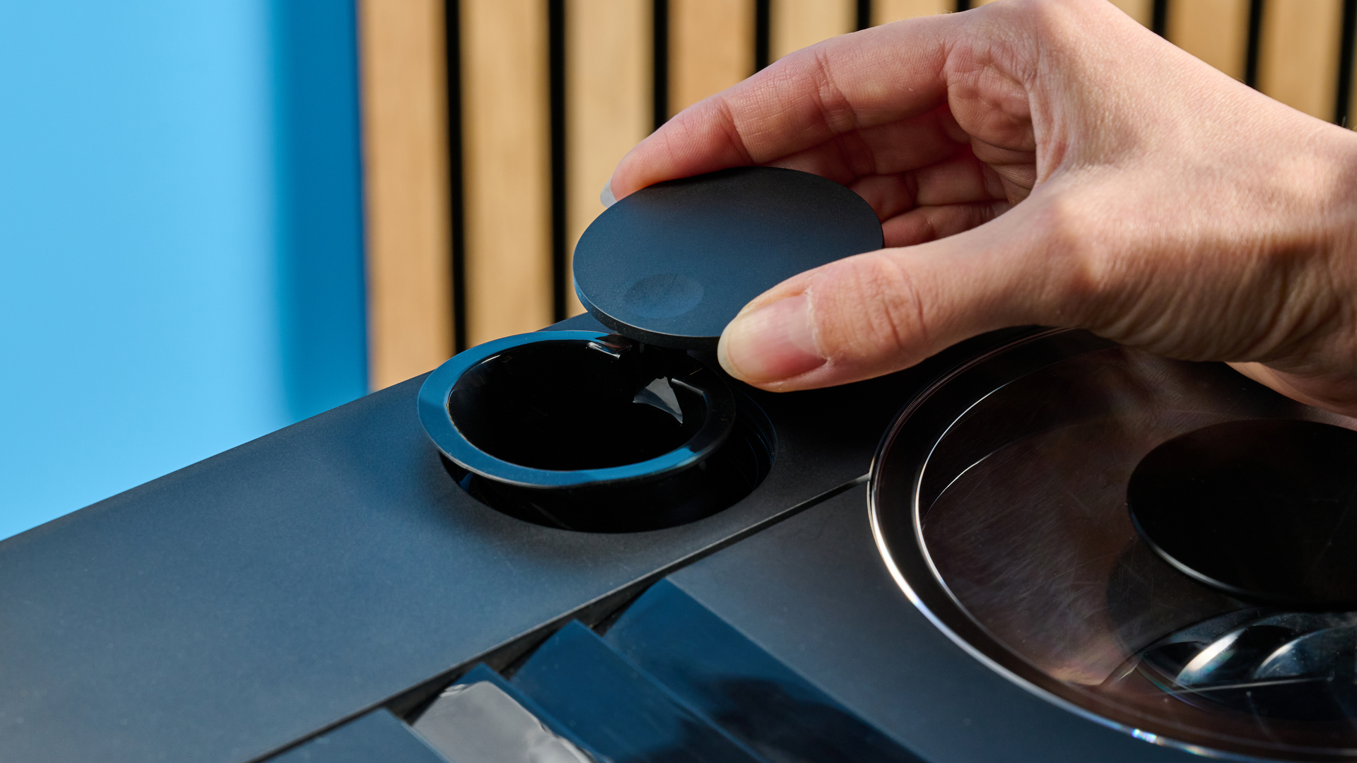 the jura c8 automatic coffee machine in piano black photographed with a blue and wood background