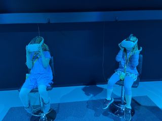Two girls sit wearing VR headsets at an immersive Monet exhibit.