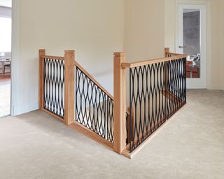 Forged steel, powder-coated black spindle staircase with light oak wood on landing by Neville Johnson