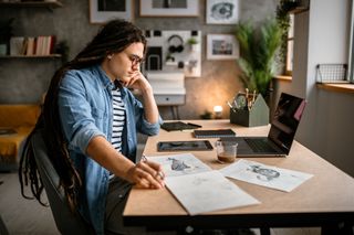 man with dreadlocks sketching in a studio