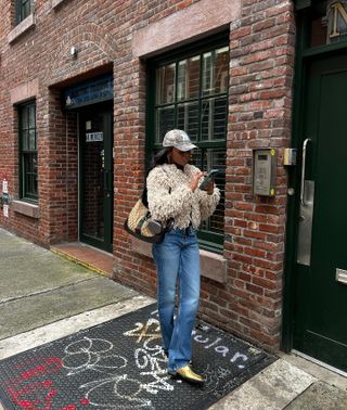 Devin wears faux fur jacket, blue jeans, and gold shoes