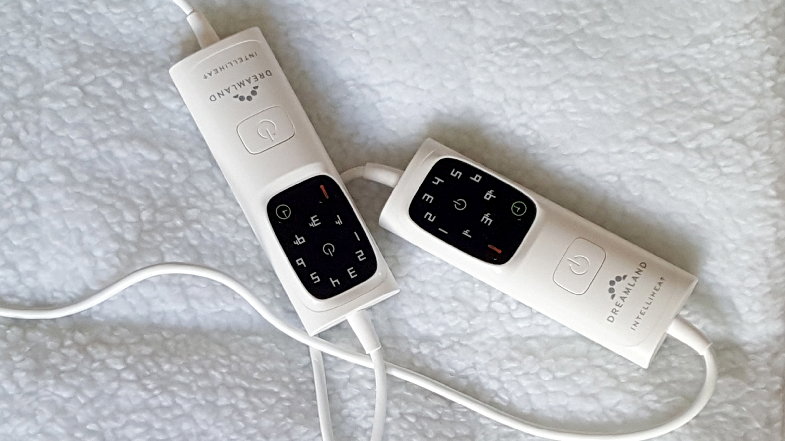 Two electric blanket controllers on a fleece electric blanket