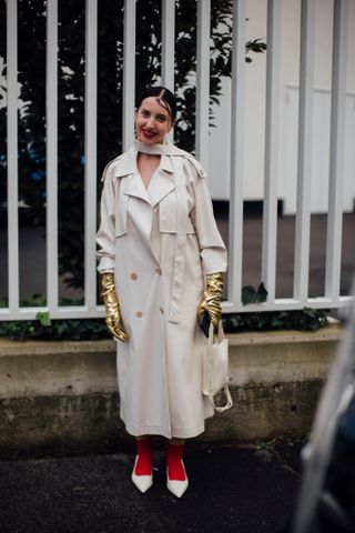 a woman in a trench coat, gold leather gloves, red tights, and white shoes