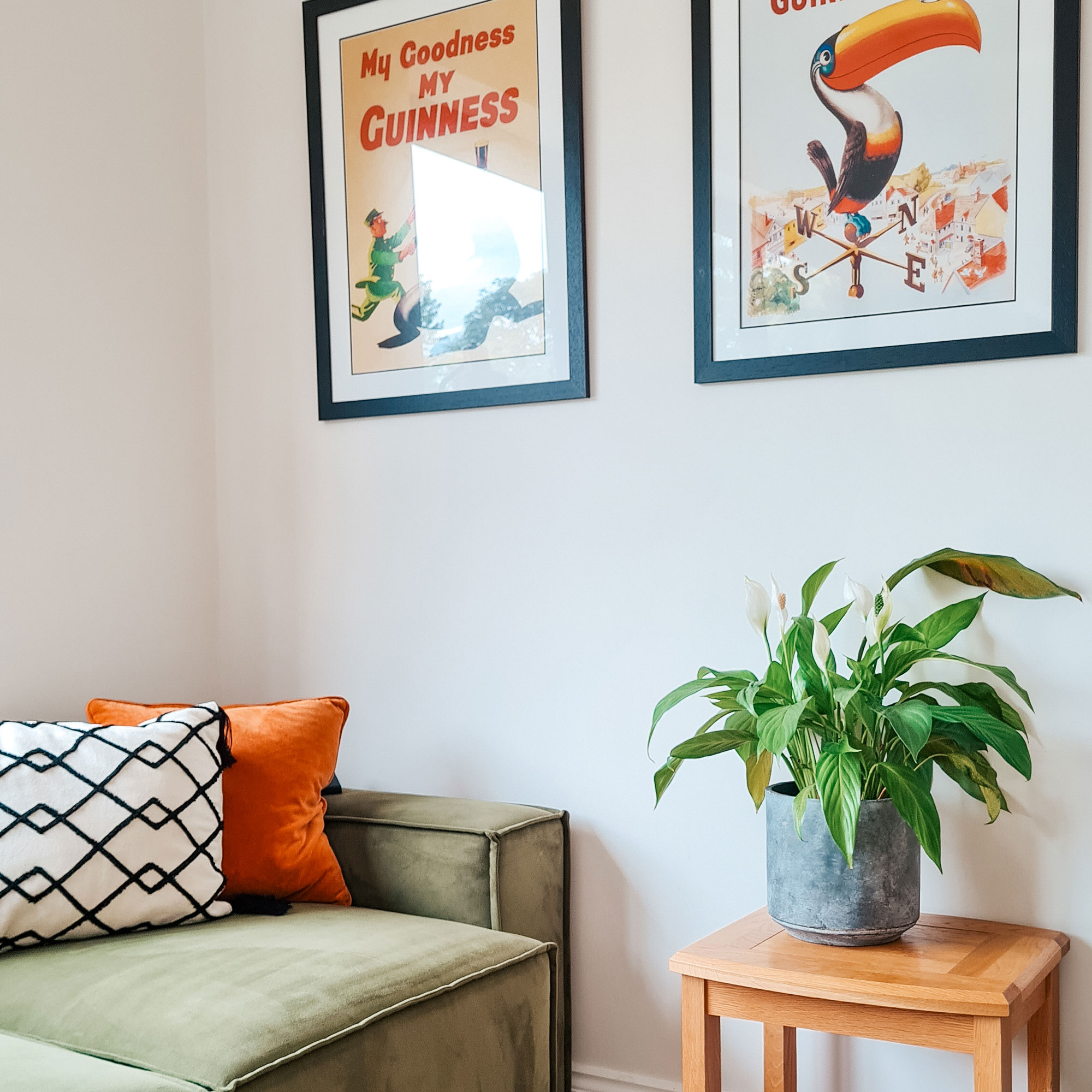 White walls with green sofa, wooden table and peace lily