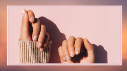 Glowing hands in sweater with knitted sleeves and with nude color manicure with gold particles on pink table