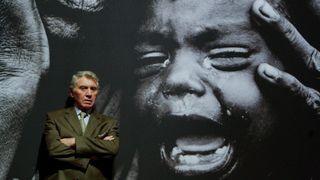 GCAB0H Photographer Don McCullin stands in front of one of his photographs on display in the Shaped by War exhibition at the Imperial War Museum North in Manchester.