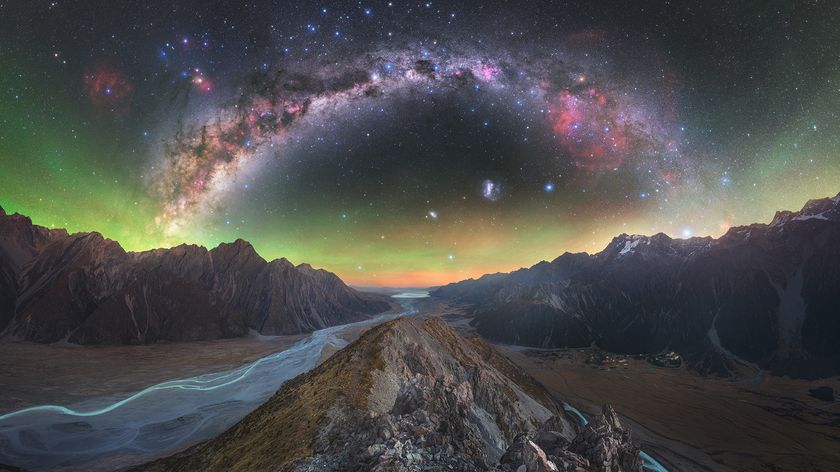 A breathtaking night sky, featuring a vibrant Milky Way arching over jagged mountains and a serene river below, evokes wonder and tranquility