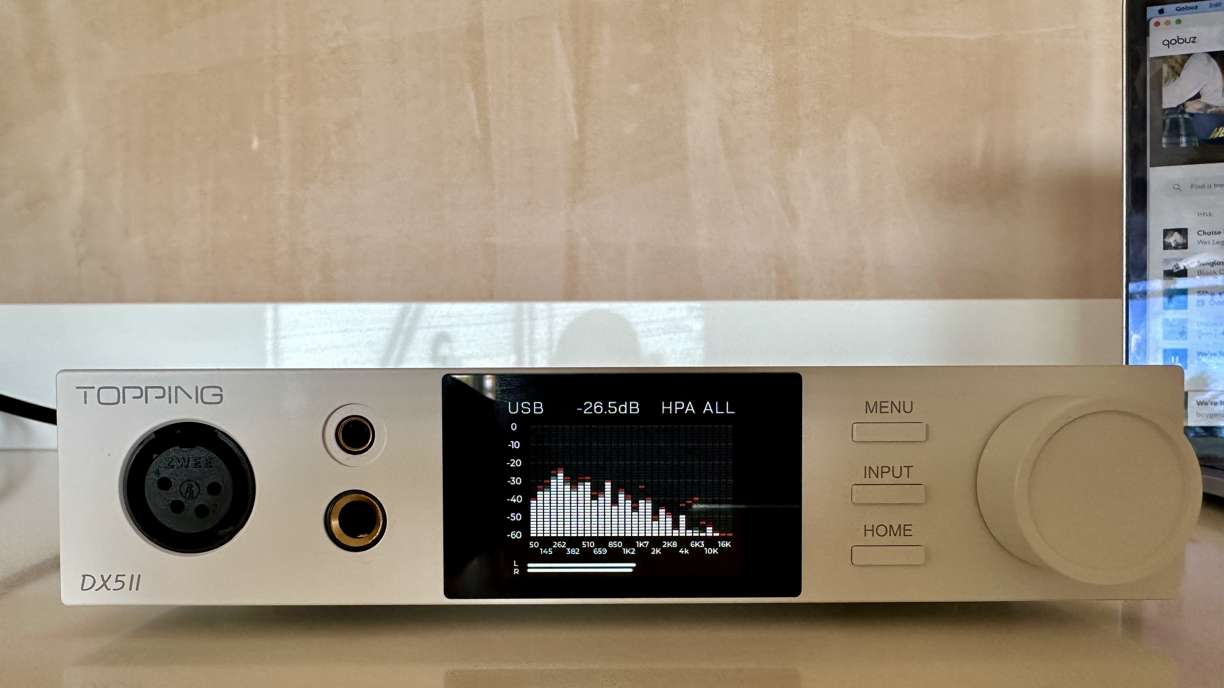 The Topping DX5 II on a light-wood table, showing the VU meter, ports and just-seen remote