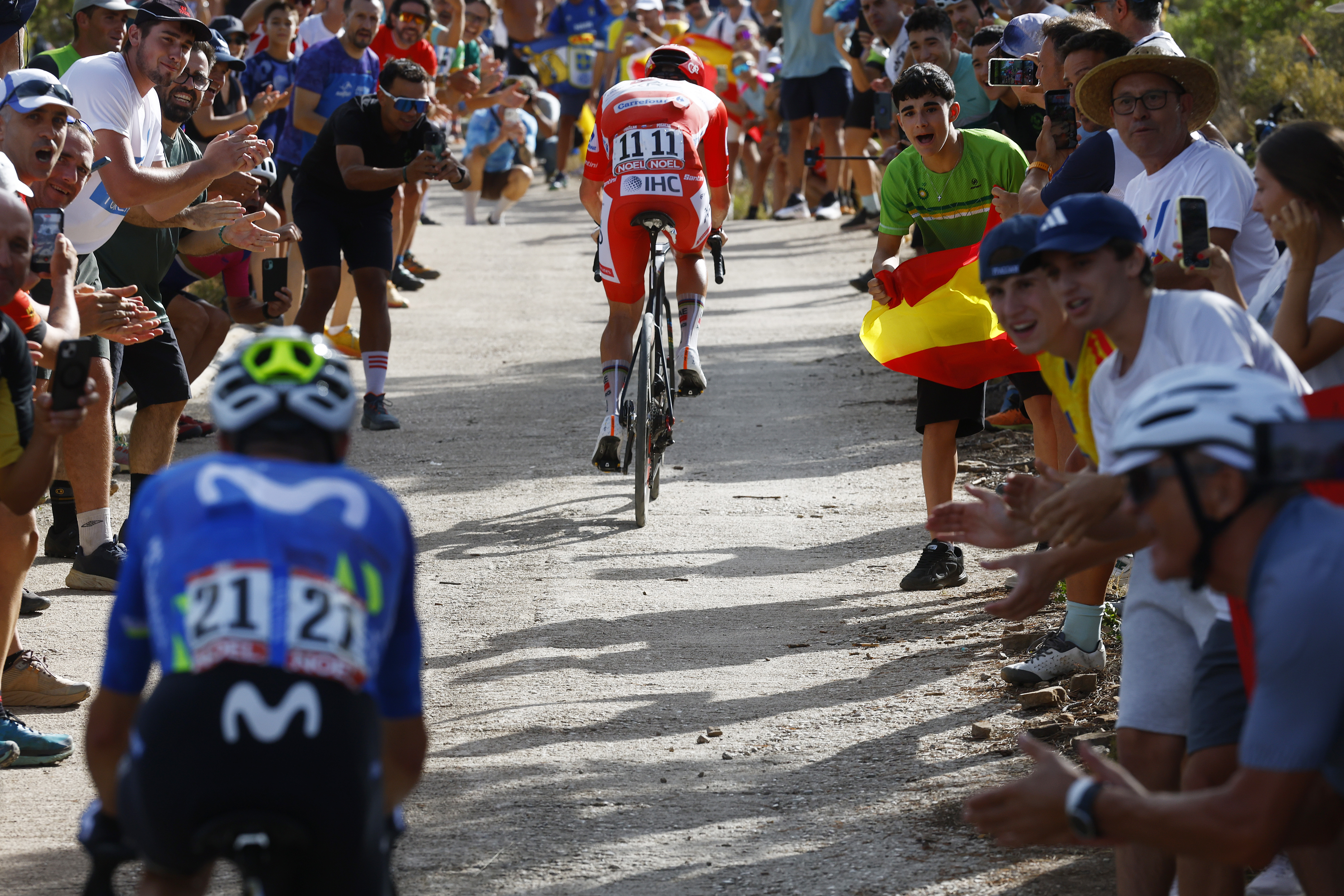 Enric Mas riding toward Pogacar on the gravel as spectators cheer