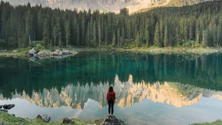 Death Doula on beating fear of death—Woman standing and looking at Lago di Carezza in Dolomites.