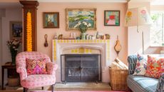 Small living room fireplace ideas are so cozy. Here is a pink living room with wall art, a fire place, a pink chair, and a pink and yellow rug