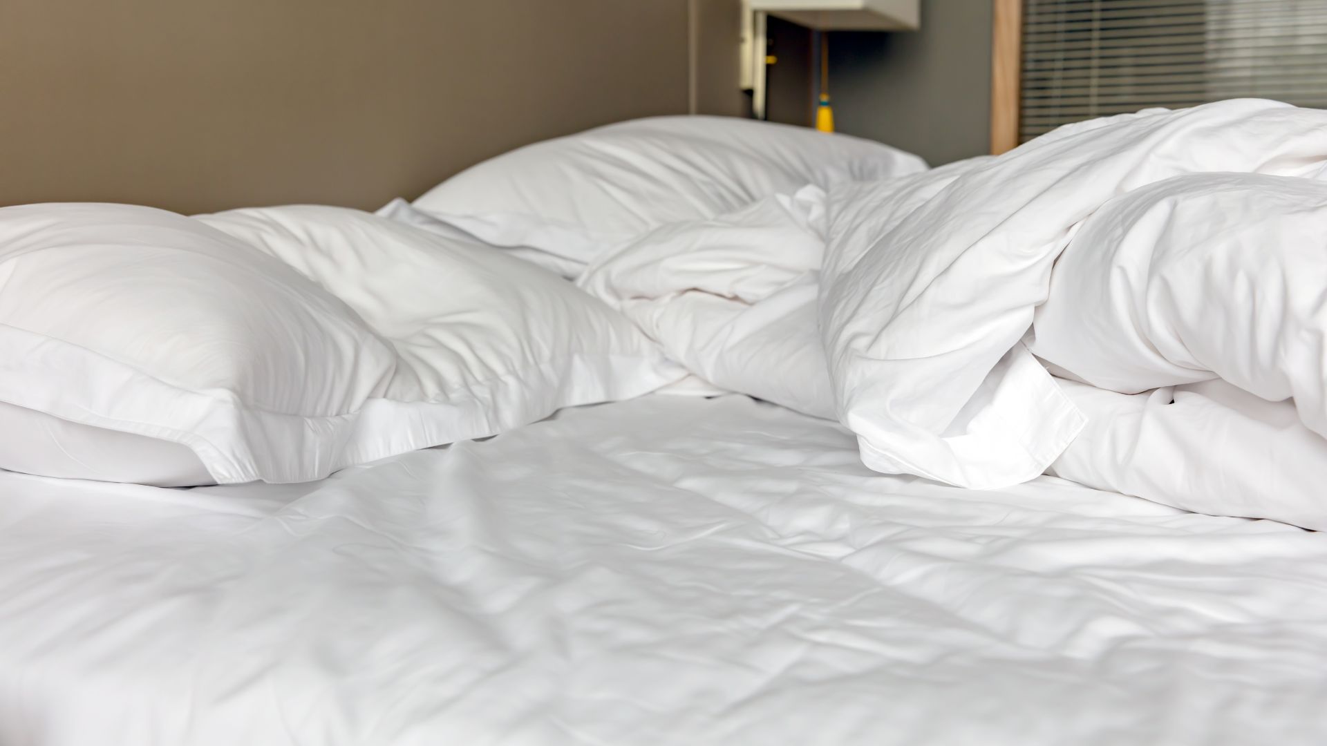 picture of white bedding on an unmade bed