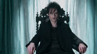 Tom Sturridge's Morpheus sits in a chair against a pale blue background in Netflix's adaptation of The Sandman