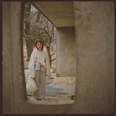 A women stands outside a concrete wall